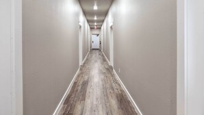 A long, narrow hallway with white walls and a wooden floor. - Centrally Located San Marcos Unit w/ Parking! (San Marcos)