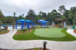 A golf course with a putting green, blue tents, and lounge chairs. - Spinnaker at Shipyard - Golf course view, walk to beach (Hilton Head Island)