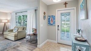 Una sala de estar con un sofá color crema, una mesita redonda y una puerta con panel de vidrio.