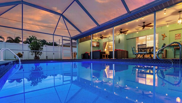 Una piscina con área techada, ventiladores de techo y luces colgantes.