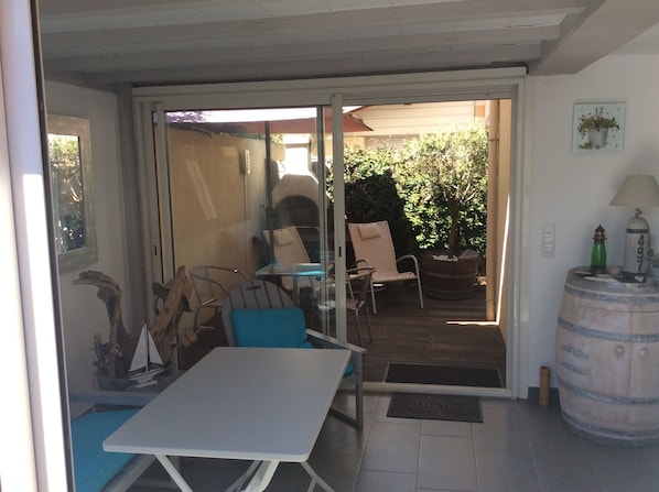 Un patio con una mesa y sillas, un barril de madera y una puerta que da a un jardín.