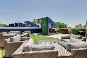 A modern outdoor patio area with wicker furniture, a green wall with a guitar, and a sign reading "Nashville."