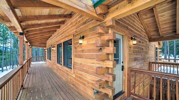 A wooden cabin with a covered porch, large windows, and a door with a small porch.