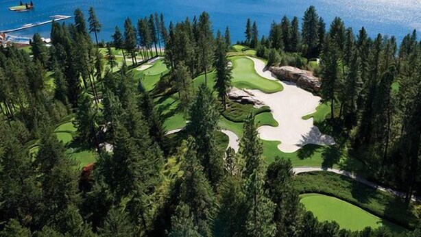 A golf course with a lake and forested area.