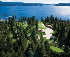 A golf course with a lake and forested area.