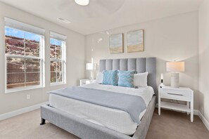 Une chambre à coucher avec un grand lit, des tables de chevet, une commode et une fenêtre donnant sur un paysage rocheux.