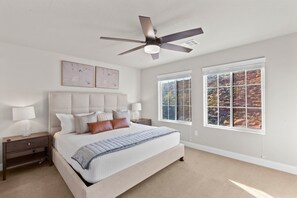 A bedroom with a large bed, two bedside tables, a ceiling fan, and a window with a view of trees. - Escondido 2343 & 2355 Retreat, Connected homes with 10 Bedrooms, sleeps 40, and endless amenities (Washington)