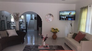 Ein modernes Wohnzimmer mit einer Couch, einem Couchtisch und einem an der Wand befestigten Fernseher.