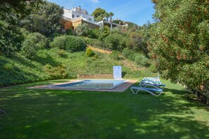 A swimming pool with lounge chairs, surrounded by lush greenery and a hillside view. - Casa semiadosada  con vistas a mar. Situada a 1.500 mts de la playa. (Begur)
