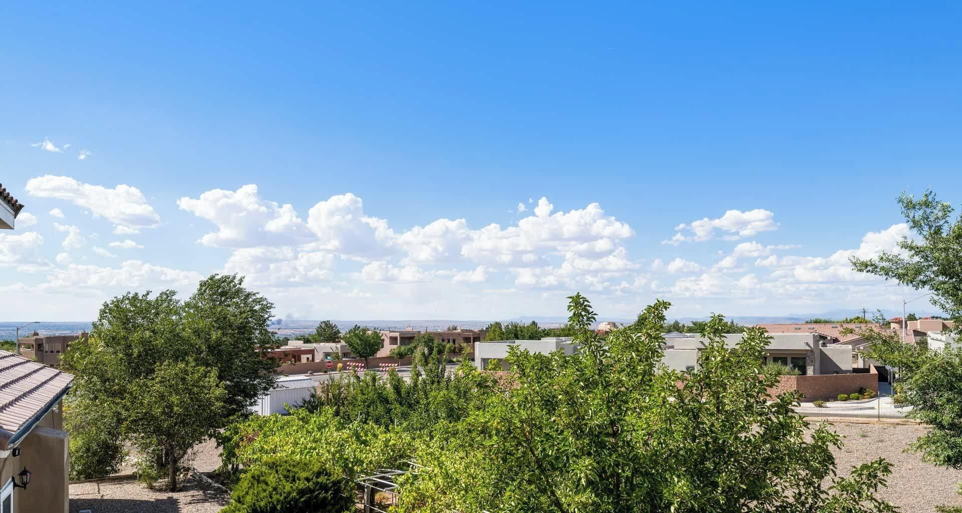 A residential area with houses, trees, and a clear sky.