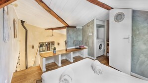 A bedroom with a wooden ceiling, a bench, a washing machine, and a door. - LE CASTELET - Cosy duplex proche du centre-ville (Toulouse)