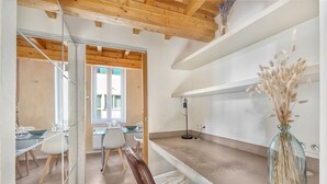 A modern kitchen with a wooden ceiling, a dining area with a glass table, and a vase with dried plants on the countertop. - LE CASTELET - Cosy duplex proche du centre-ville (Toulouse)