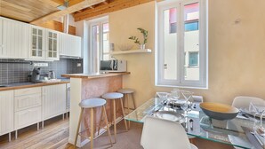 A modern kitchen with white cabinets, a bar area, and a dining table set for four. - LE CASTELET - Cosy duplex proche du centre-ville (Toulouse)