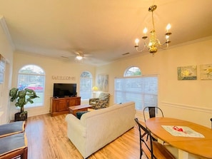 Relax in this stylish living room with a high ceiling, TV, sofa, and dining area.