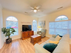 Relax in this inviting living room with a large TV, comfortable sofa, and cozy armchair.
