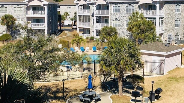 A multi-story hotel with balconies, a swimming pool, and outdoor seating areas. - Amazing cute & cozy condo in the center of MB (Myrtle Beach)
