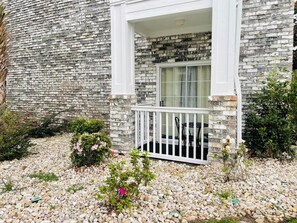Guests can enjoy a balcony overlooking a lush garden with a gravel pathway.
