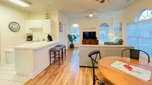 A modern kitchen with a central island, a dining area with a table, and a living room with a sofa. - Amazing cute & cozy condo in the center of MB (Myrtle Beach)