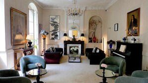 Un salón espacioso con chimenea, un piano de cola y muebles elegantes.