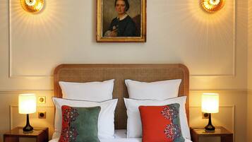A hotel room with a bed, two nightstands, two lamps, and a framed portrait on the wall.