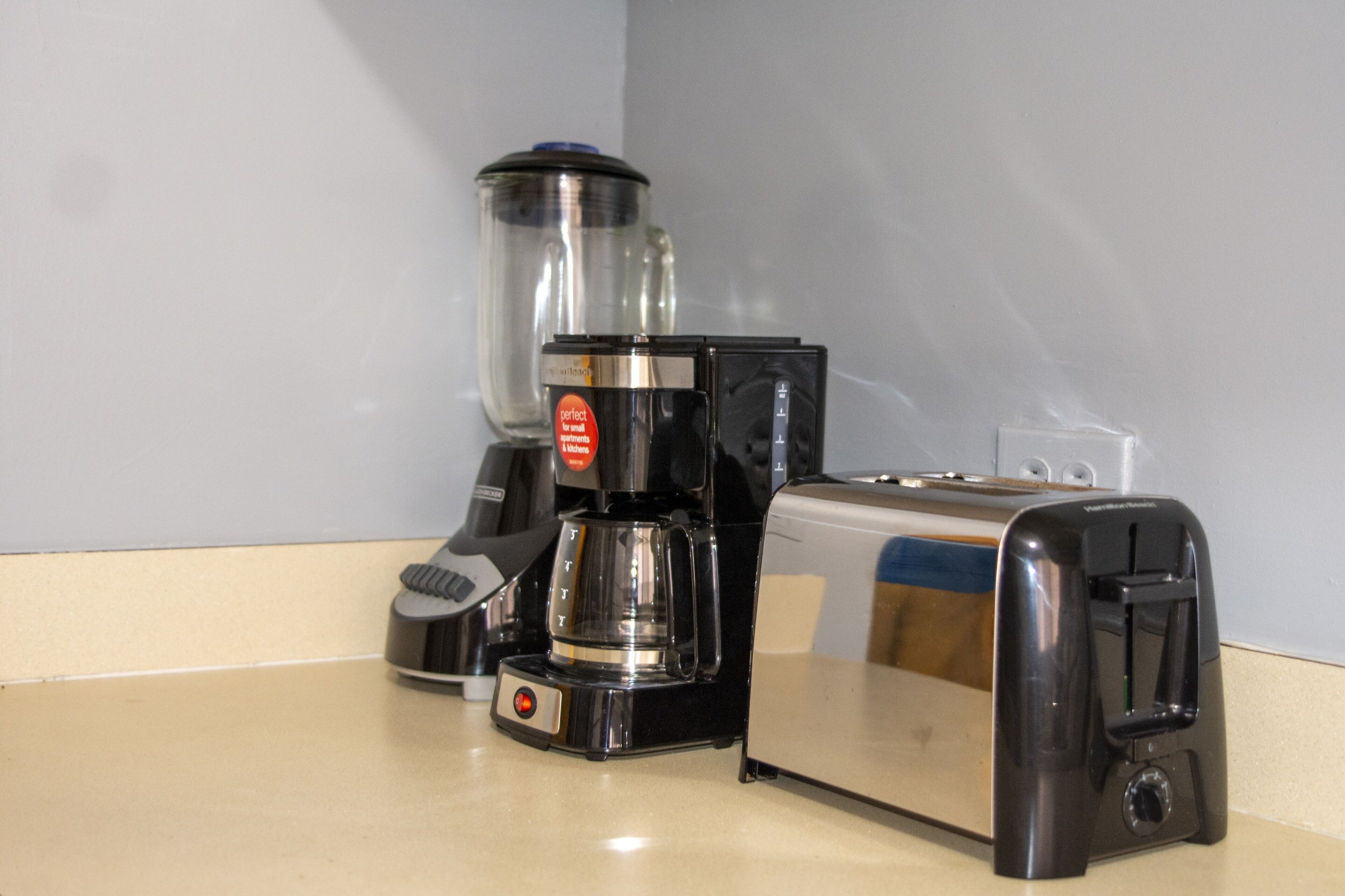 En köksbänk med en kaffebryggare, en brödrost och en mixer.