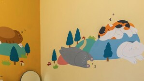 Un dormitorio infantil con escritorio, silla y un mural en la pared con animales dormidos.