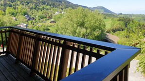 Ein Balkon mit Blick auf eine gebirgige Landschaft und ein Dorf darunter.