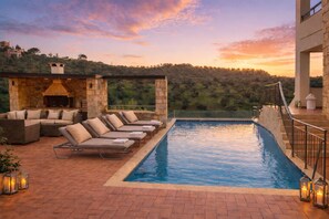 An outdoor pool area with lounge chairs, a stone barbecue, and a view of the surrounding landscape. - Unique four bedroom villa with amazing mountain and breathtaking sea view. (Στάλος)