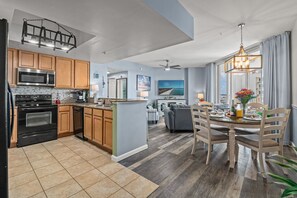 A modern kitchen with a central island, wooden cabinets, and a dining area with a table and chairs.