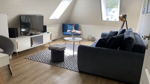 En moderne stue med fjernsyn, sofa og et lille bord.