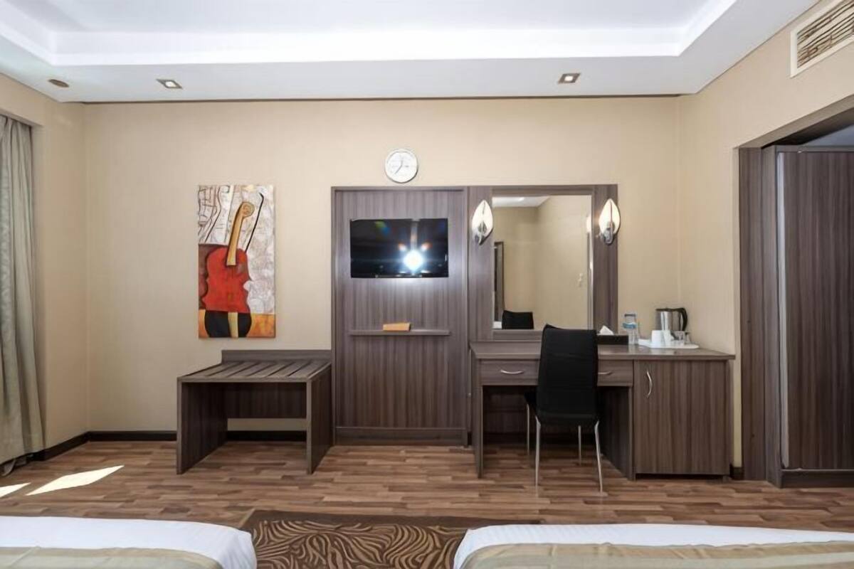 A hotel room with a bed, a desk, a chair, a TV, and a wardrobe.