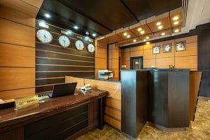 A reception desk with clocks displaying different time zones, a duty manager sign, a printer, and a counter with a computer. - Pearl Swiss Hotel (Dubai)