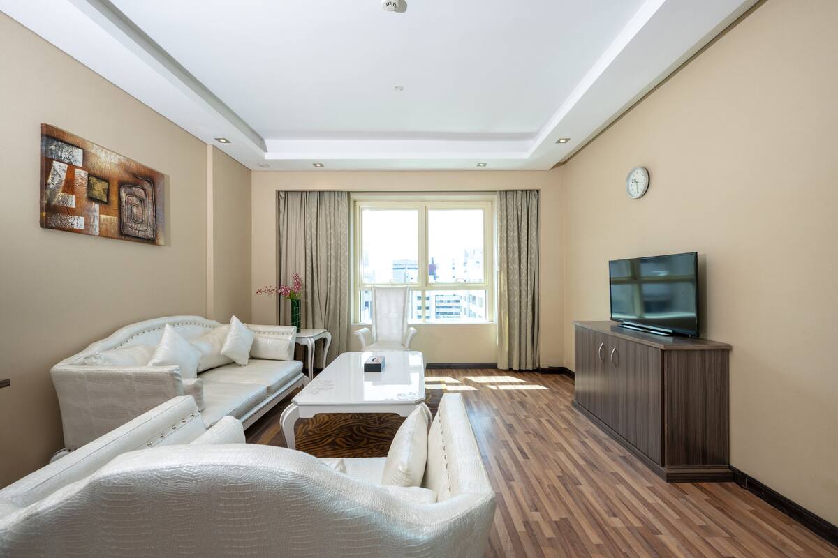 A modern living room with a sofa, a coffee table, a TV, and a dining area.