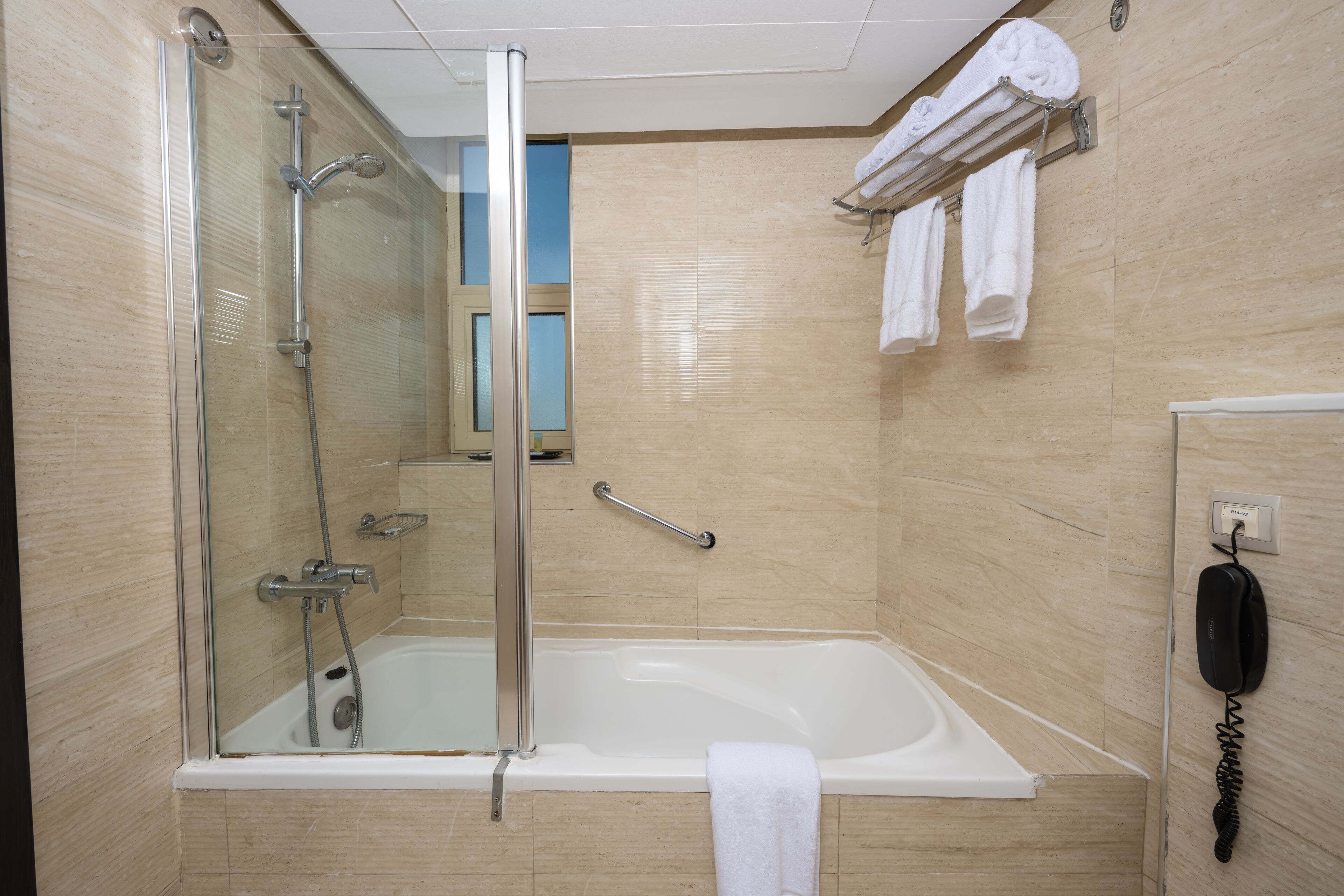 A modern bathroom with a glass-enclosed shower, a bathtub, and a towel rack with multiple towels.