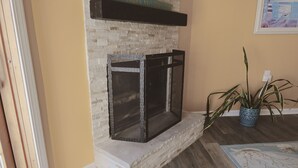 A fireplace with a stone surround, a potted plant, and a framed picture on the wall. - Beautiful waterfront summer getaway-7 minutes to beach! (Stafford Township)
