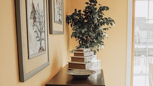 A hallway with a wooden table, a potted plant, framed artwork, and a glass bowl. - Beautiful waterfront summer getaway-7 minutes to beach! (Stafford Township)