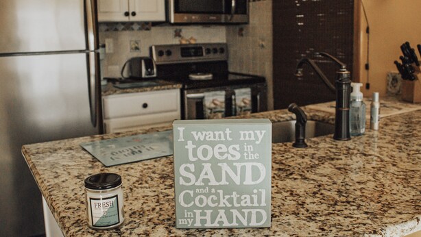 A kitchen with a granite countertop, a stainless steel refrigerator, a microwave, and a sign with a humorous message. - Beautiful waterfront summer getaway-7 minutes to beach! (Stafford Township)