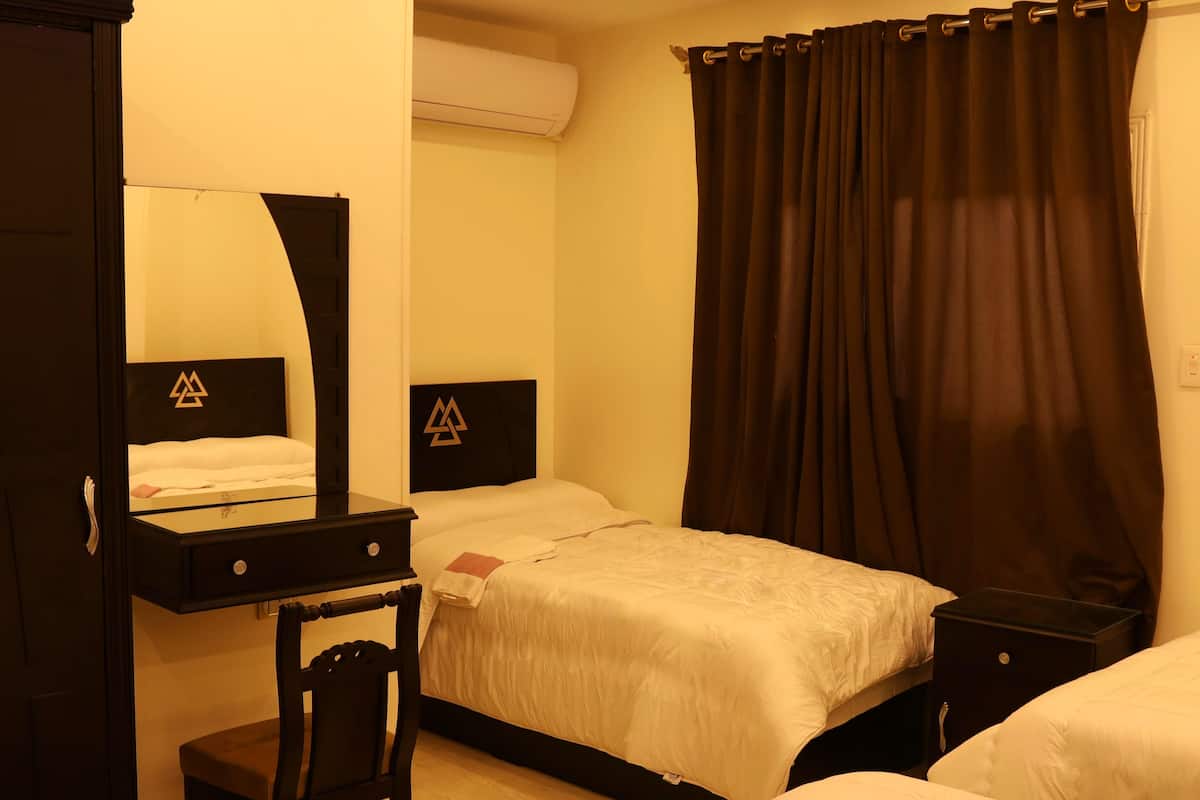 A hotel room with two beds, a desk, a chair, and a wardrobe.
