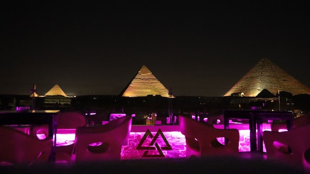 A nighttime view of the pyramids with illuminated seating areas in the foreground.
