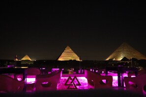 A nighttime view of the pyramids with illuminated seating areas in the foreground. - Magic Pyramids inn (Giza)