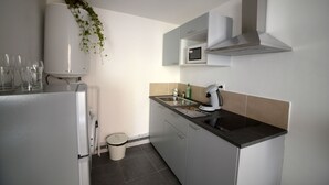 A modern kitchen with white cabinets, a microwave, a sink, and a coffee maker. - Large studio near the ancient theater in Orange (Orange)