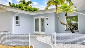 Ein modernes Haus mit einer geschwungenen Auffahrt, einer weißen Tür und einem kleinen Fenster.
