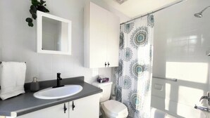 A modern bathroom with a white sink, toilet, and shower area. - Amazing Loft in Saint-Roch (Québec)