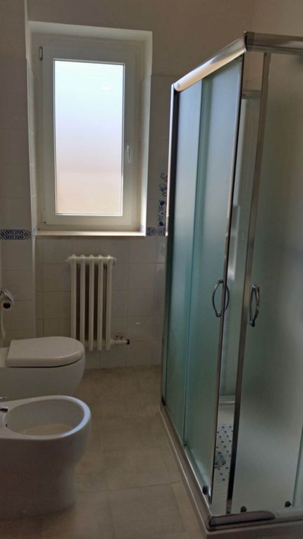 A bathroom with a toilet, bidet, and a glass shower enclosure.