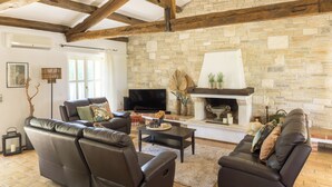 Una sala de estar con chimenea de piedra, sofás de cuero y pared de piedra.