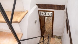 Una escalera con barandilla metálica, pasamanos de madera y suelo estampado.