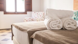 Una cama bien hecha con una colcha color crema y una toalla blanca enrollada encima.