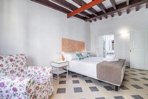 Une chambre à coucher avec un lit, une table de chevet et un fauteuil à motifs floraux.