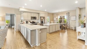 A modern kitchen with a central island, built-in appliances, and a dining area with a table and chairs. - Stylish 4BR Majestic Retreat • Stunning Views of Table Rock Lake! (Branson)