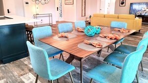 A modern dining area with a wooden table, blue chairs, and a yellow sofa in the background.